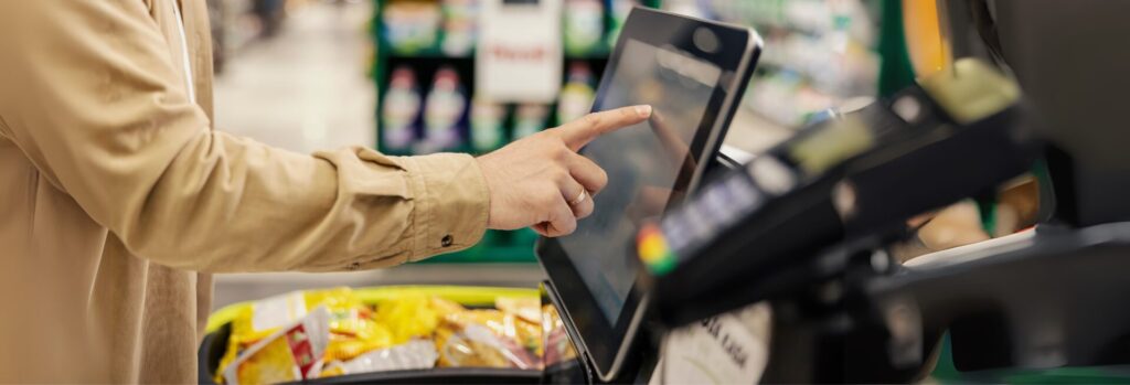 Un monsieur payant sur une caisse en libre-service dans un  commerce de détail grâce à un système basé sur l'automatisation et l'IA