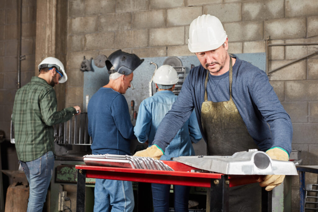 Operatore siderurgico lavora un pezzo di metallo.
