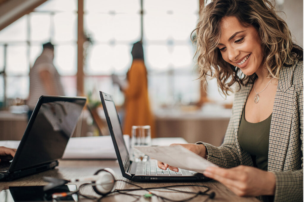 Donna lavora al computer mentre analizza un documento.