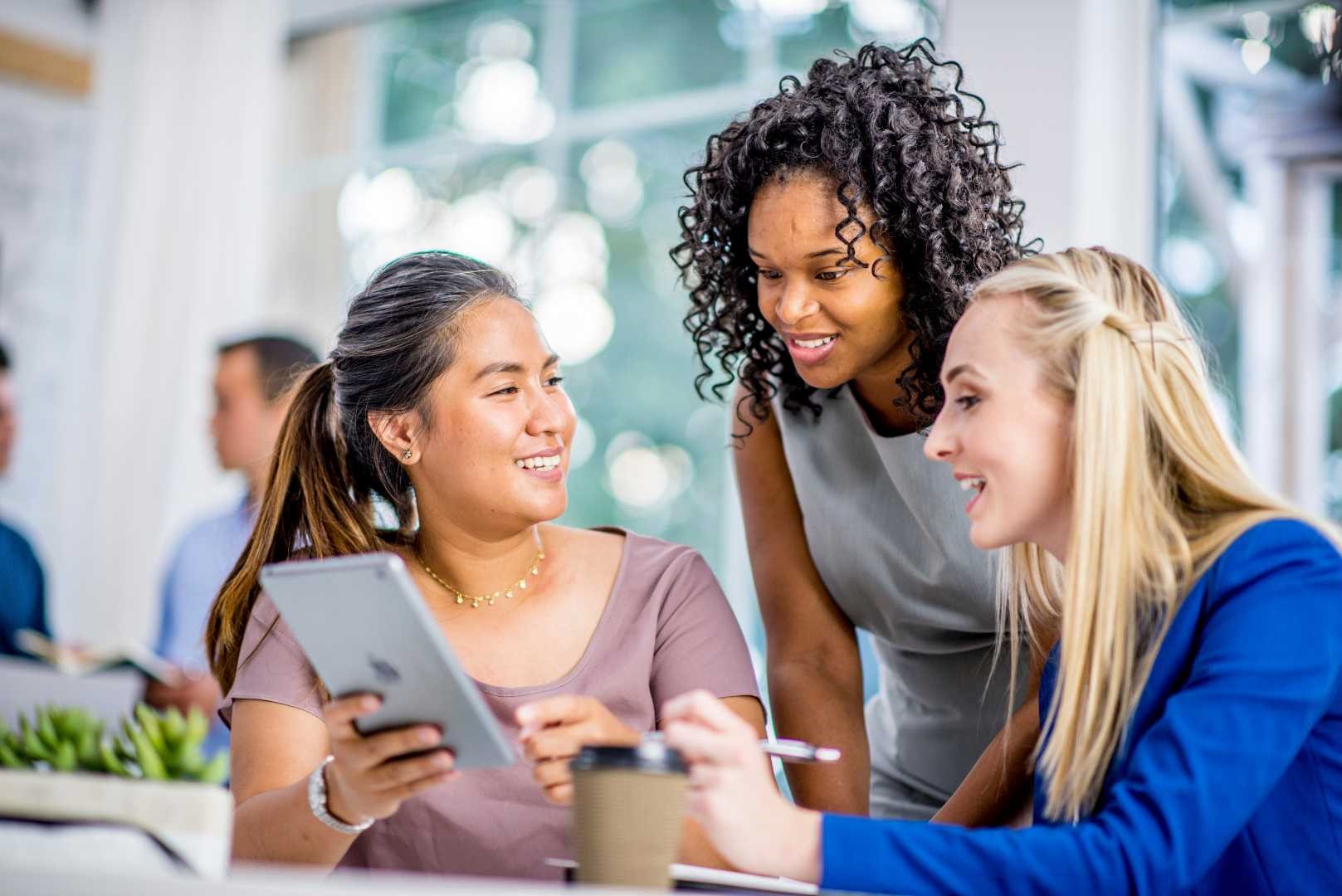 Gruppo di lavoro composto da professionisti, seduti attorno a un tavolo, utilizzano tablet per consultare documenti o condividere idee, in un ambiente collaborativo e moderno