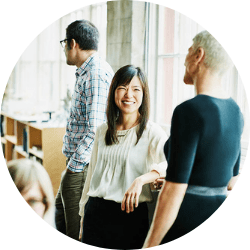 Team di Leyton composto da donne e uomini in abbigliamento professionale, che parlano tra di loro in un ambiente di ufficio moderno, mostrando collaborazione e lavoro di squadra.