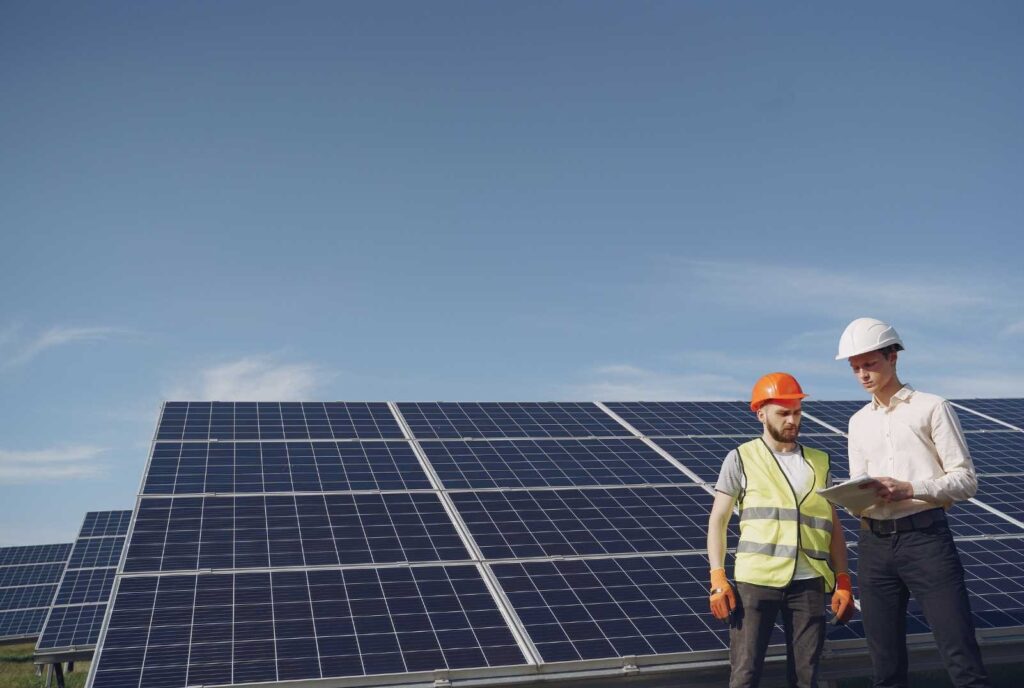 Due operai lavorano vicino ad un impinto fotovoltaico.