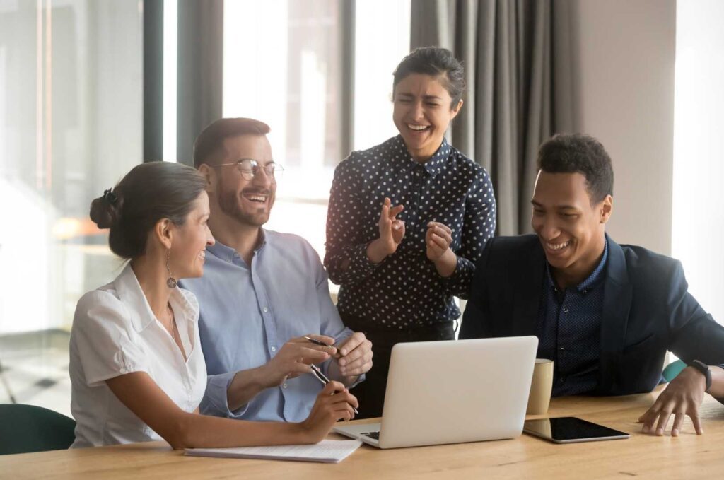 Un gruppo di persone sedute attorno a un tavolo, mentre utilizzano un laptop per discutere e collaborare. FAQ Transizione 5.0