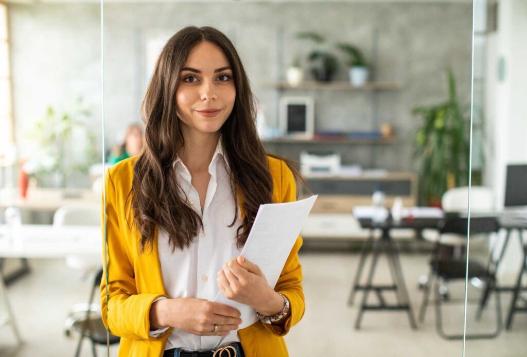 Una donna in abito sorride in ufficio.