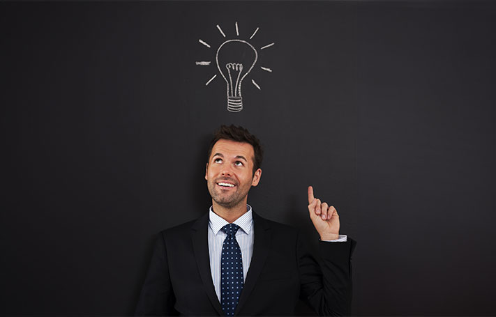 Un uomo sorride e indica una lampadina diesgnata sopra la sua testa.