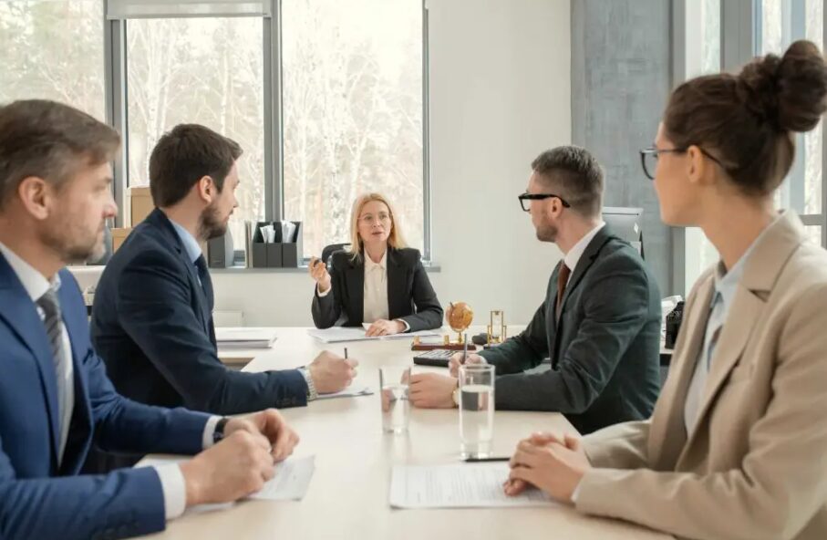 Un gruppo di professionisti seduti attorno a un tavolo di conferenza durante una riunione di lavoro.