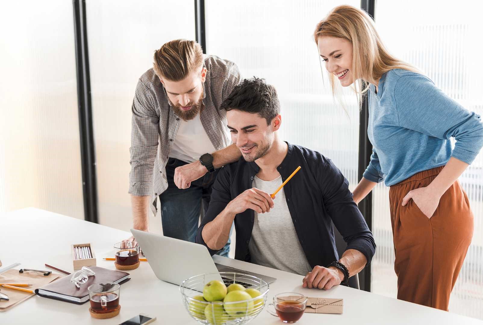 Dei membri di un team di lavoro consultano insieme un laptop.