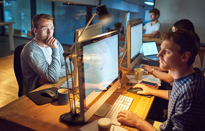 Un gruppo di persone lavora su computer in un ufficio moderno e collaborativo.