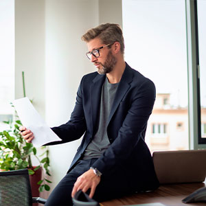 Un uomo seduto sulla scrivania di un ufficio, mentre consulta un documento.