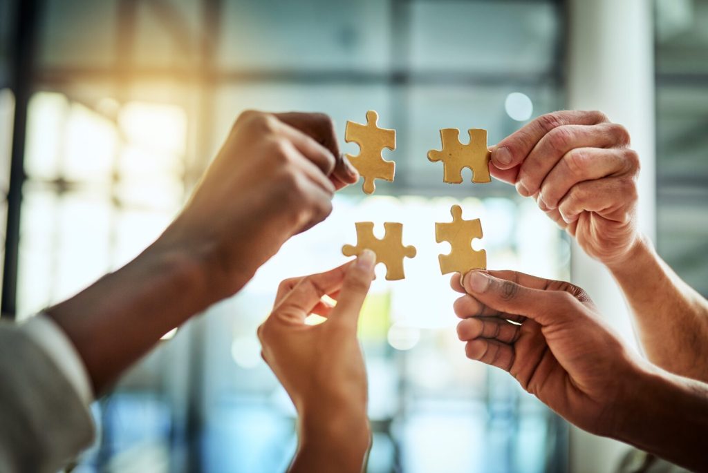 quattro mani con pezzi di puzzle combacianti