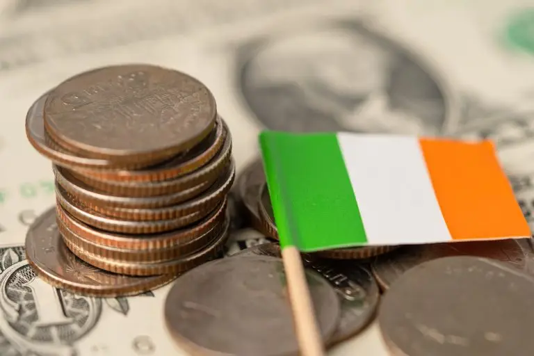 Stack of coins and a small Irish flag on bills, symbolising Ireland's economy and finance.