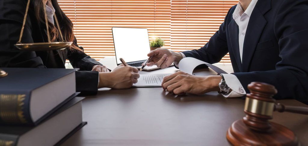 Businessman and lawyer discussing business contract document for legal advice in lawyer's office.
